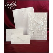 Stříbřité a blýskavé svatební oznámení v průhledné košilce s natištěnými rostlinnými motivy a se stříbrně rámovaným srdcem